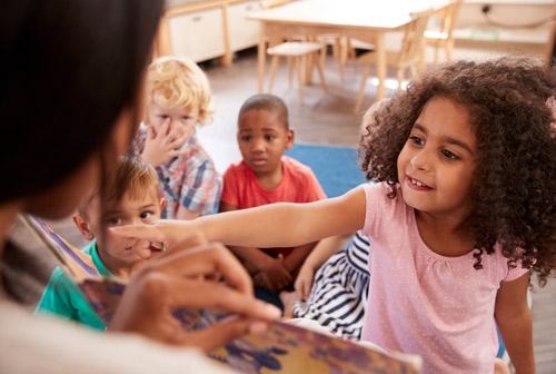 Children listening to a teacher read a book