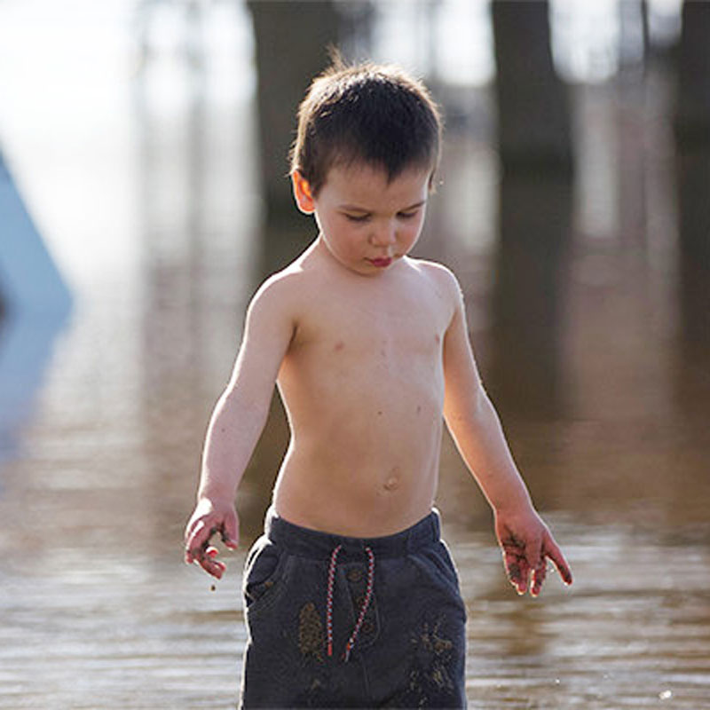 young child walking in flooded street