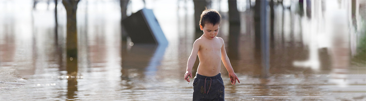 young child walking in flooded street